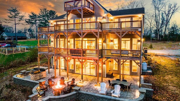 A multi-story wooden house with a balcony, outdoor seating area, and a fire pit. - Lakefront • HotTub • Luxe Baths • Fire Pit Retreat (Mineral)