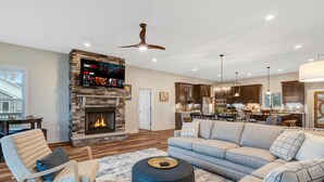 A spacious living room with a stone fireplace, a modern kitchen, and a dining area. - Lakefront • HotTub • Luxe Baths • Fire Pit Retreat (Mineral)