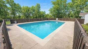 A rectangular swimming pool with a wooden deck and a wooden fence surrounding it.