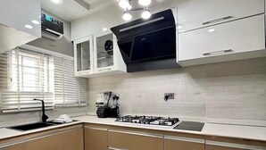 A modern kitchen with white cabinets, a gas stove, and a built-in oven. - Icempire Signature (Lagos)