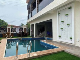 Piscina com escada de metal, rodeada por um deck em padrão losango.