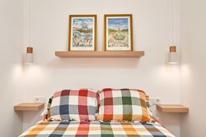 A bedroom with a checkered bedspread, two framed pictures on the wall, and bedside tables with lamps. - Apartment 'Abril' with Sea View (Bremen)