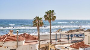 A coastal view with a beach, palm trees, and a building with a sign '3 MONKEYS'. - Apartment 'Abril' with Sea View (Bremen)
