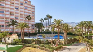 A multi-story hotel with a pool area, palm trees, and a mountain backdrop. - Apartment 'Abril' with Sea View (Bremen)