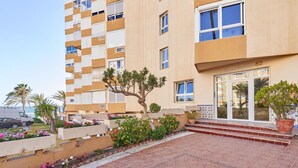A multi-story building with balconies, a gated entrance, and a small garden area with potted plants. - Apartment 'Abril' with Sea View (Bremen)