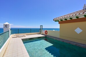 Un espace piscine avec vue sur la mer, une bouée de sauvetage et un poste de surveillance pour les sauveteurs.