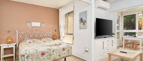 Ein Schlafzimmer mit Bett, Fernseher, Schreibtisch und Fenster.