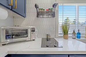 A modern kitchen with a built-in toaster oven, a spice rack, and a window with a view of the outside. - Rucker Avenue Cozy Bungalow (Everett)