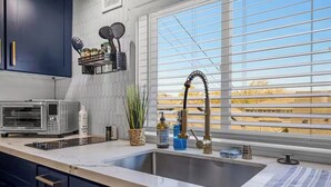 A kitchen with a double sink, a built-in oven, and a window with blinds.