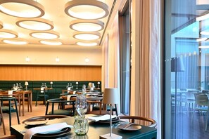 Un restaurant avec des luminaires ronds au plafond, des tables et des chaises en bois.