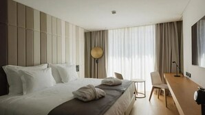 Ein modernes Hotelzimmer mit einem großen Bett, einem Schreibtisch und einem Stuhl.