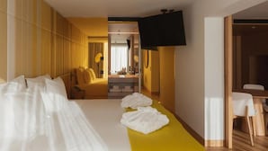 Une chambre d’hôtel avec un lit, un bureau, une chaise, une télévision et une salle de bain visible à travers une porte ouverte.