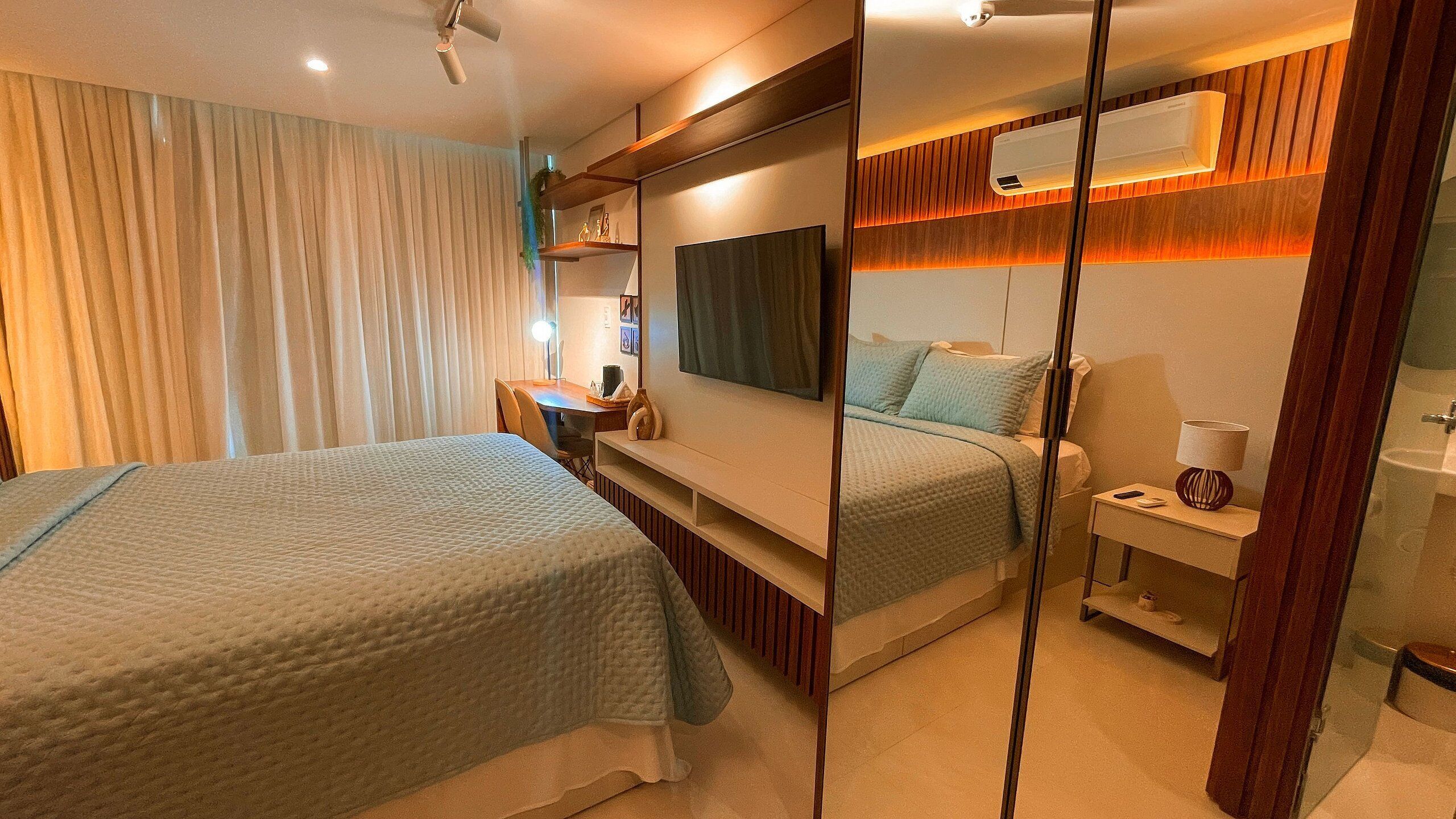 Ein Hotelzimmer mit zwei Betten, einem Schreibtisch, einem Spiegel und einem Badezimmer.