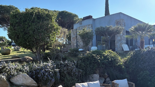 Un espace aménagé au bord de la piscine, avec des meubles en bois et une vue sur un bâtiment moderne.