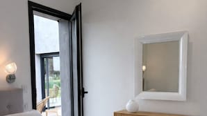 Une chambre à coucher avec un lit, une table de chevet, un miroir et une fenêtre.