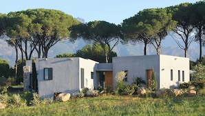 Une maison moderne à deux étages, dotée d’un toit plat, de murs extérieurs blancs et d’un petit porche à l’avant.