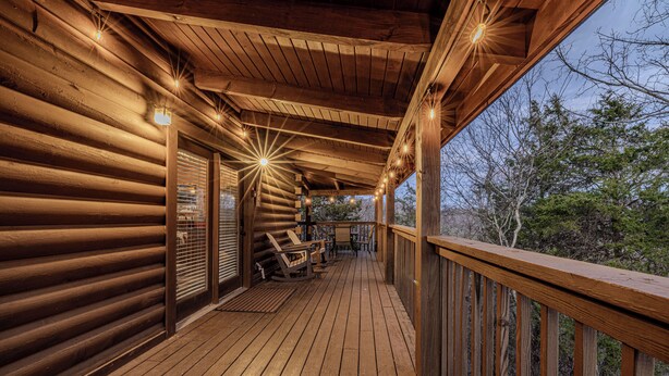 A wooden deck with a railing, wooden walls, and string lights. - Enchanted Eagle cabin, 3 bedroom, with Hot tub and games room (Sevierville)