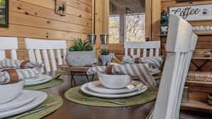 A wooden interior with a dining table set for four, white chairs, a coffee sign, and a rustic decor. - Enchanted Eagle cabin, 3 bedroom, with Hot tub and games room (Sevierville)