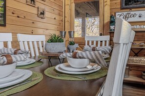 A wooden interior with a dining table set for four, white chairs, a coffee sign, and a rustic decor. - Enchanted Eagle cabin, 3 bedroom, with Hot tub and games room (Sevierville)