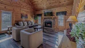 A cozy log cabin interior with a fireplace, a sofa set, and a dining table. - Enchanted Eagle cabin, 3 bedroom, with Hot tub and games room (Sevierville)