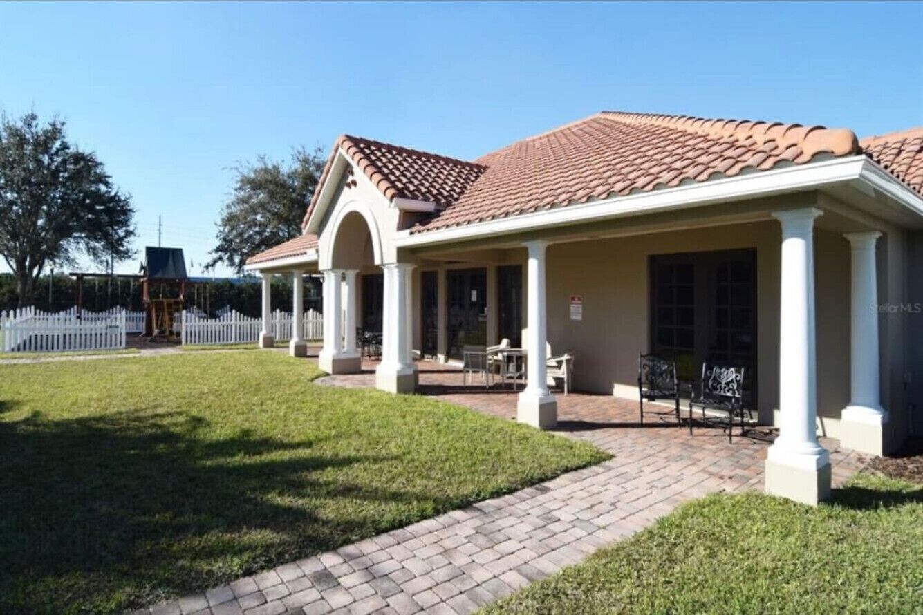 A two-story building with a tiled roof and a covered patio area with outdoor seating.