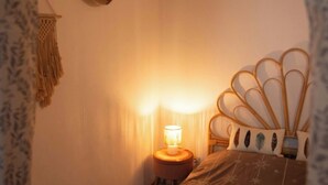 A cozy bedroom with a bed, a bedside lamp, a wall hanging, and a wooden headboard.