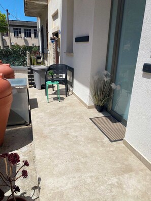 Un espace patio avec une table et des chaises, une plante en pot et une porte-fenêtre coulissante.