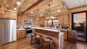 Une cuisine rustique avec des meubles en bois, des appareils électroménagers en acier inoxydable et un grand îlot central doté de tabourets.