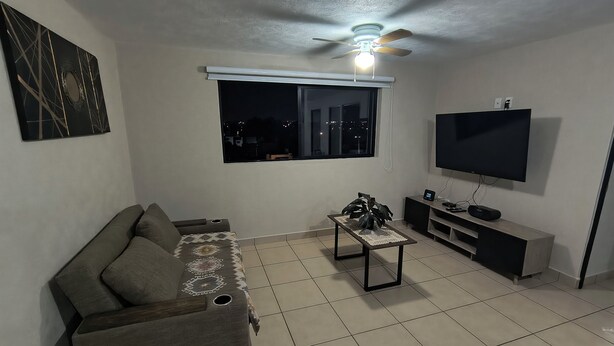 Ein Wohnzimmer mit einer Couch, einem Couchtisch, einem Fernseher und einem Deckenventilator.