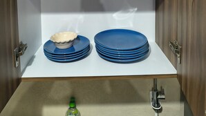 Eine Küchenschrank mit blauen Schüsseln, Tellern und einem weißen Behälter.