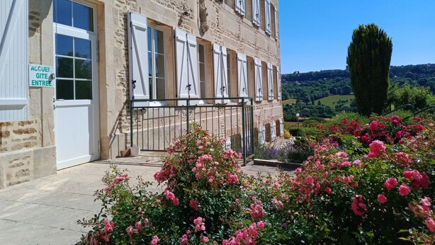 A stone building with white shutters and a sign indicating guest entry.