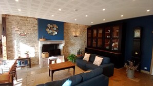 A living room with a stone wall, a fireplace, a blue sofa, and a wooden cabinet.