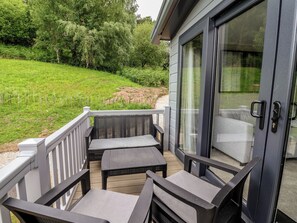 A covered outdoor seating area with a view of a grassy landscape and trees. - The Pines 2 Bedrooms (Northwich)