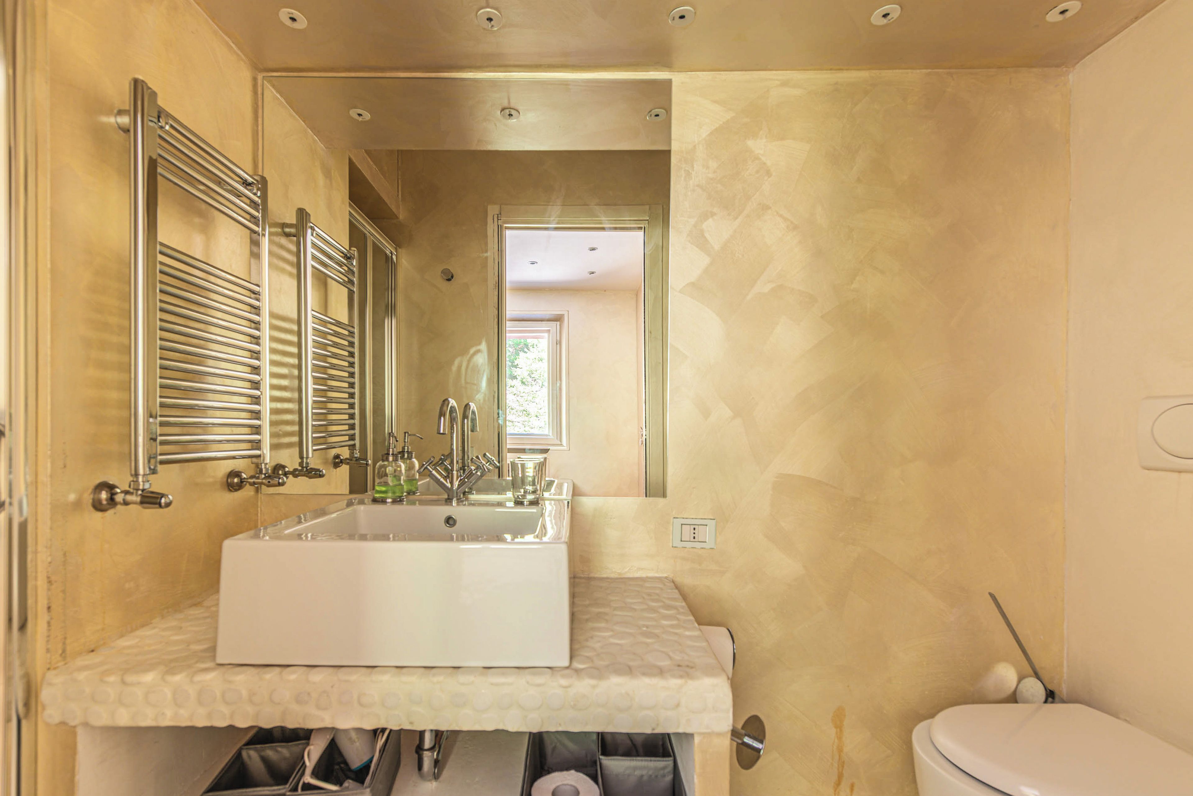 A bathroom with a large rectangular sink, a toilet, and a mirror.