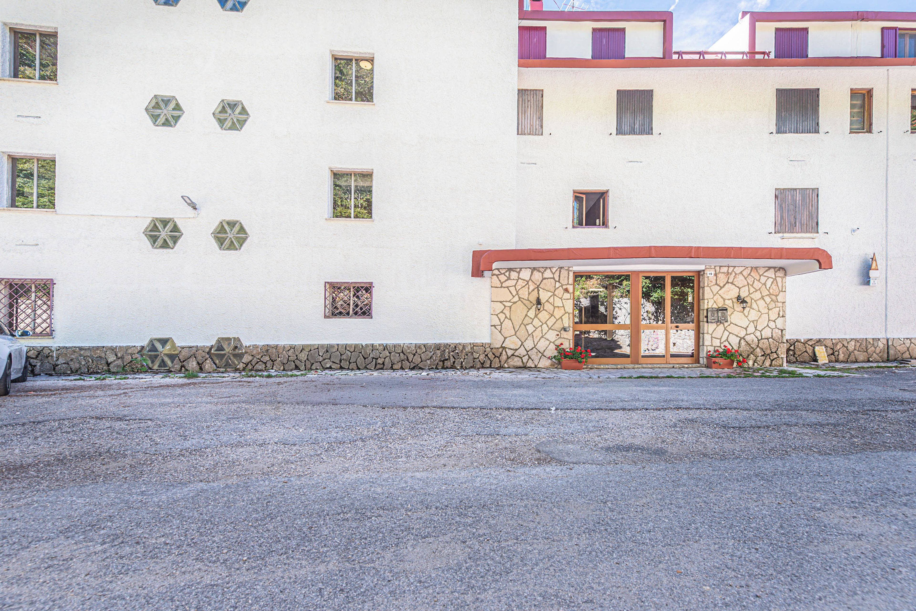 Un edificio con varias ventanas, fachada de piedra y una pequeña entrada con puerta.