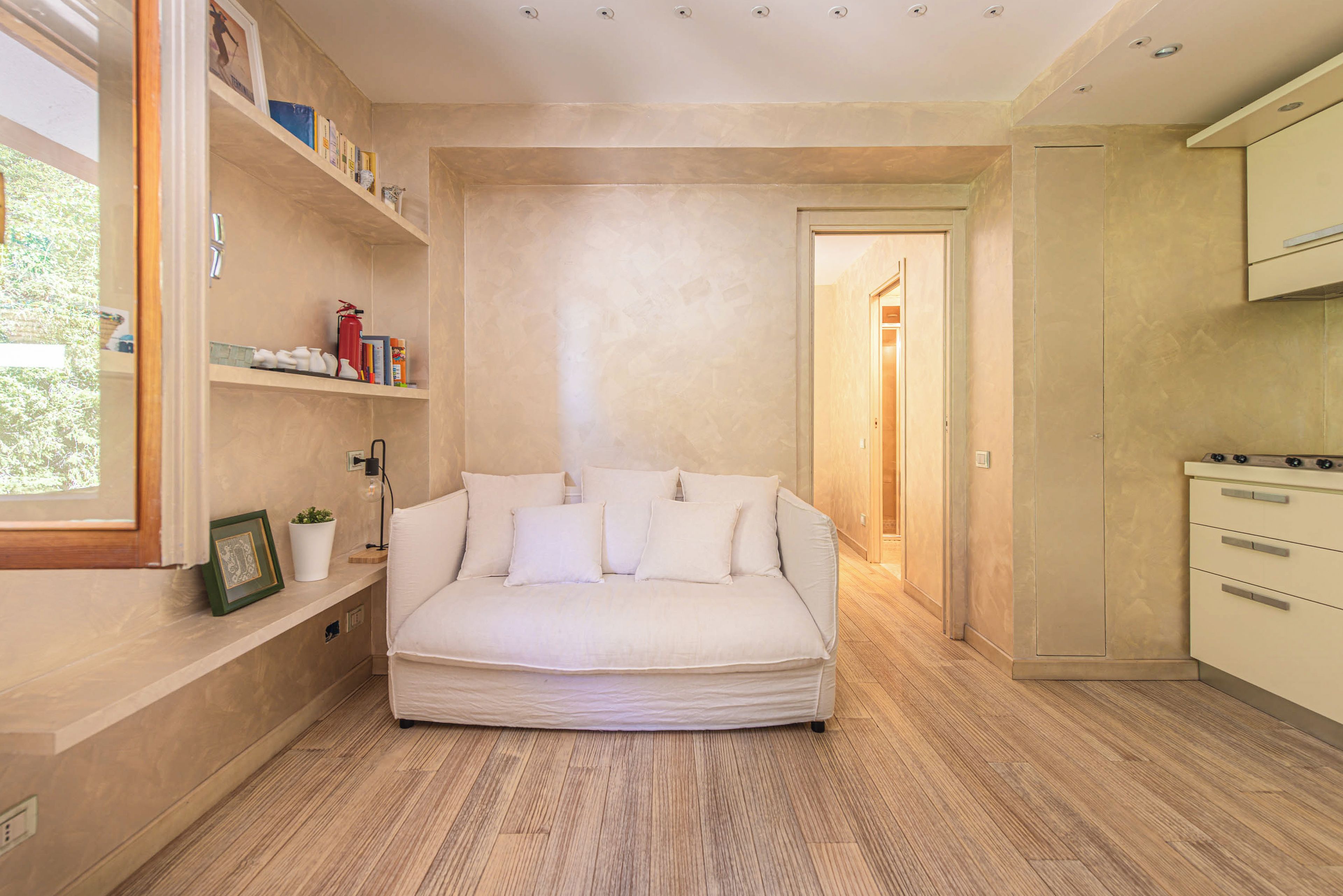 Une chambre moderne avec un canapé intégré, une table de chevet, une étagère remplie de livres et une fenêtre.