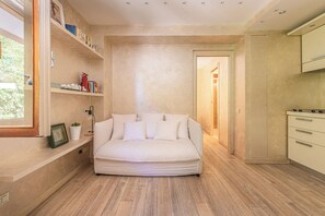 Un dormitorio moderno con sofá integrado, una mesita de noche, una estantería con libros y una ventana.