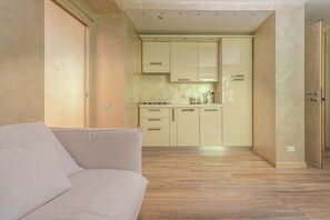 A compact living space with a sofa, kitchenette, and wooden flooring. - La Casina (Pian De' Valli)