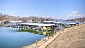 A marina with docks and boats, a covered boat launch ramp, and a clear sky. - Lake Views, Resort Perks! Osage Beach Retreat (Osage Beach)