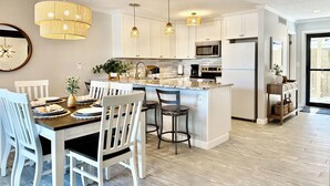 A modern kitchen with white cabinets, a central island, bar stools, and pendant lighting. - Lake Views, Resort Perks! Osage Beach Retreat (Osage Beach)