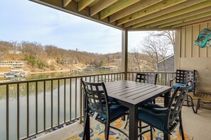 A covered outdoor area with a table and chairs, overlooking a body of water and a hilly landscape. - Lake Views, Resort Perks! Osage Beach Retreat (Osage Beach)