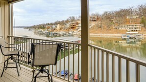 A balcony with two chairs, overlooking a marina with boats and a river. - Lake Views, Resort Perks! Osage Beach Retreat (Osage Beach)