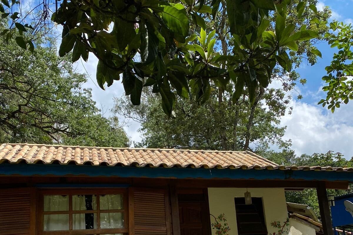 Une petite maison avec un toit en tuiles, des volets en bois et un banc à l’extérieur.