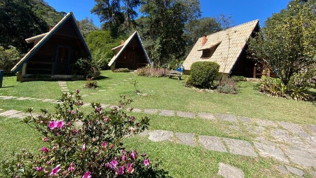 A row of triangular-roofed cabins with stone pathways and lush greenery. - Cabanas Do Visconde (Itatiaia)