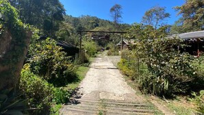 A rural pathway leading to a house with a signboard. - Cabanas Do Visconde (Itatiaia)