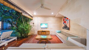 A living room with a TV, sofa, and a wooden coffee table. - Stylish 4BR Canggu Villa • Private Pool & Sundeck • 8 Min to Beach (Badung Regency)