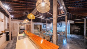 A spacious kitchen with a long wooden counter, hanging wicker light fixtures, and a high ceiling with exposed beams. - Stylish 4BR Canggu Villa • Private Pool & Sundeck • 8 Min to Beach (Badung Regency)