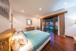 A bedroom with a bed, a wooden dresser, a desk, a chair, and a large window with curtains. - Stylish 4BR Canggu Villa • Private Pool & Sundeck • 8 Min to Beach (Badung Regency)