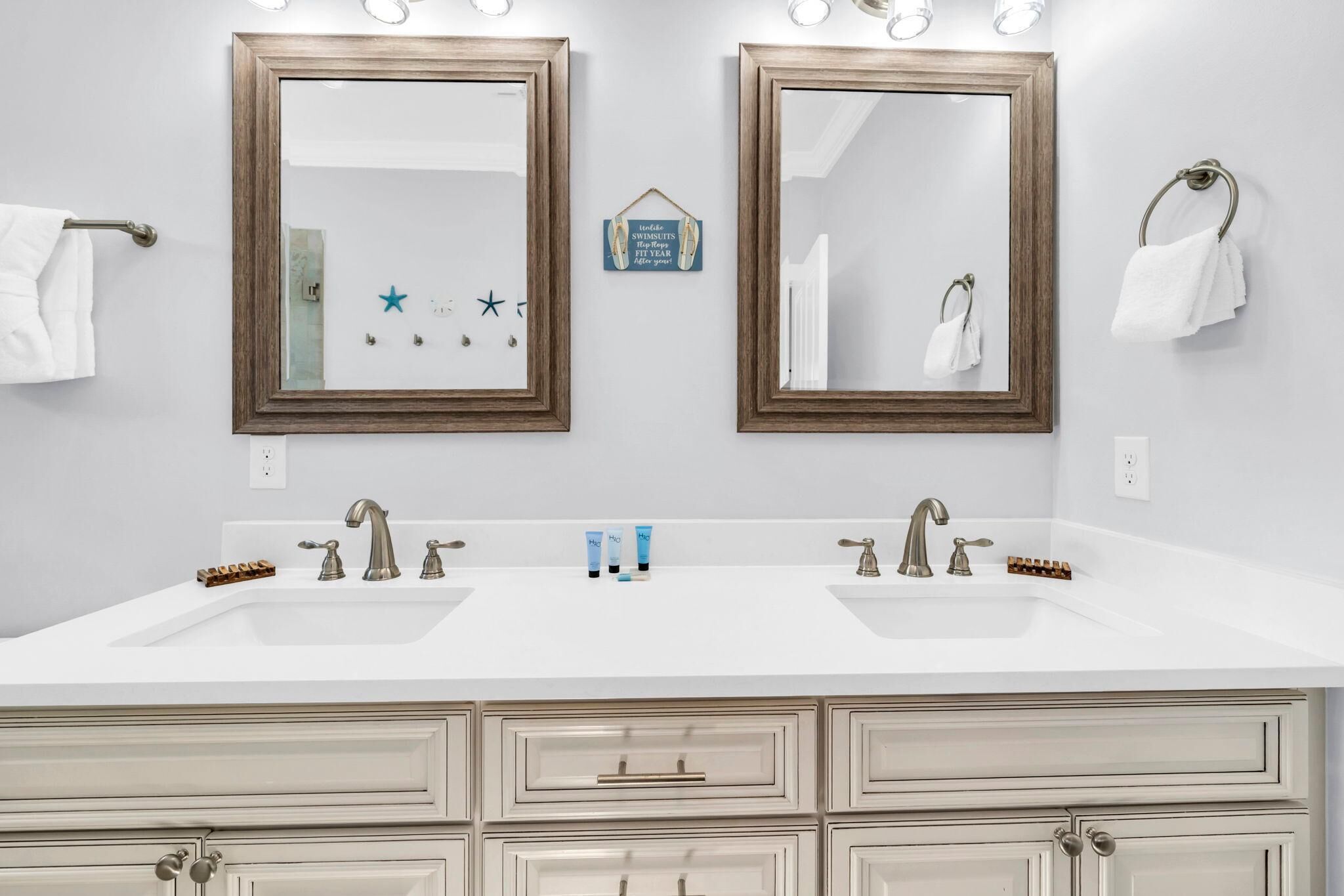 A bathroom with two mirrors, a double sink, and a vanity with drawers.