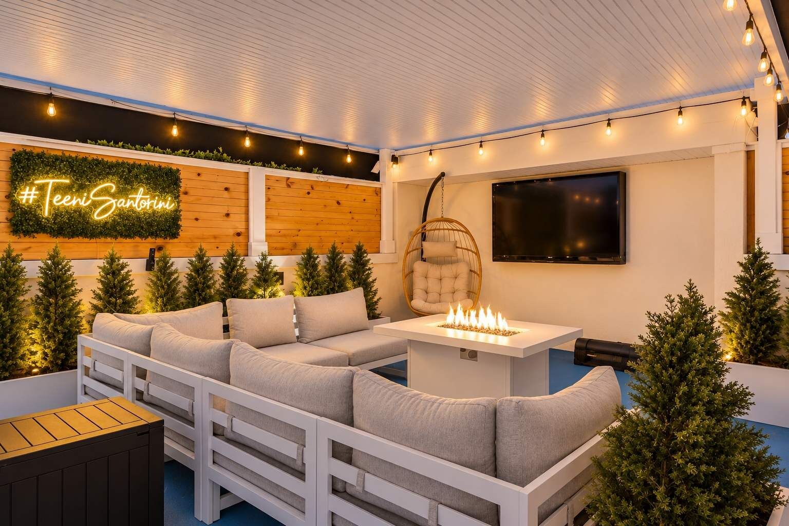Un área de estar al aire libre acogedora con un sofá blanco, una silla colgante y una chimenea.
